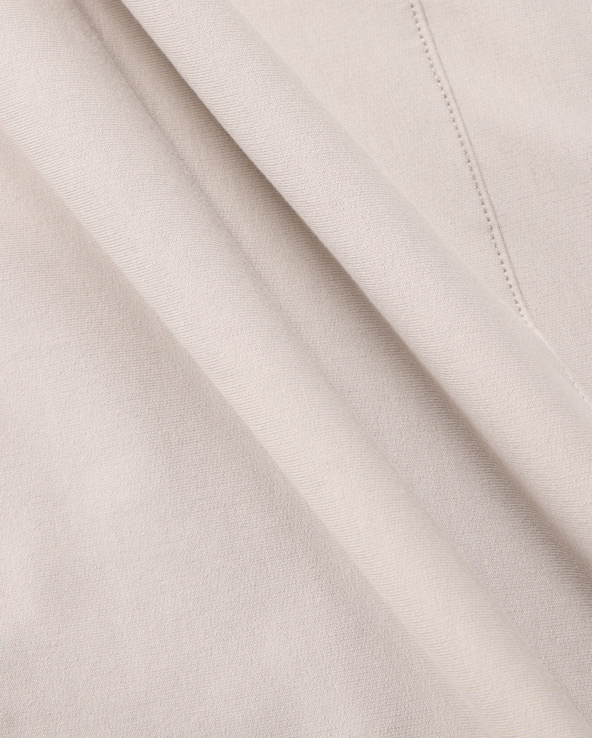 Close-up of a soft, beige Micro French terry fabric with delicate folds. The material appears smooth and lightweight, with visible stitching details on one side. The color is consistent throughout, giving a uniform and elegant appearance—perfect for crafting the MENS WALTER LIGHTWEIGHT HOODIE - B6H476D200 by Psycho Bunny.