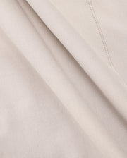 Close-up of a soft, beige Micro French terry fabric with delicate folds. The material appears smooth and lightweight, with visible stitching details on one side. The color is consistent throughout, giving a uniform and elegant appearance—perfect for crafting the MENS WALTER LIGHTWEIGHT HOODIE - B6H476D200 by Psycho Bunny.