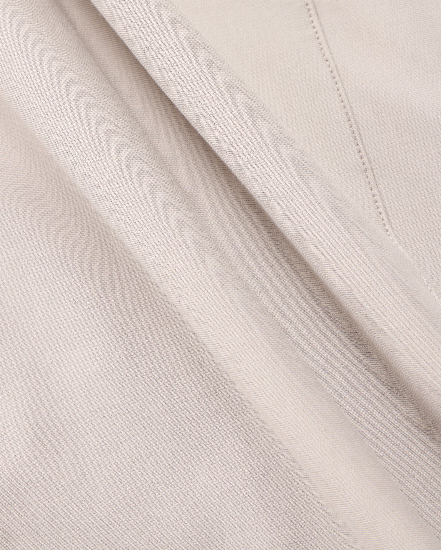 Close-up of a soft, beige Micro French terry fabric with delicate folds. The material appears smooth and lightweight, with visible stitching details on one side. The color is consistent throughout, giving a uniform and elegant appearance—perfect for crafting the MENS WALTER LIGHTWEIGHT HOODIE - B6H476D200 by Psycho Bunny.