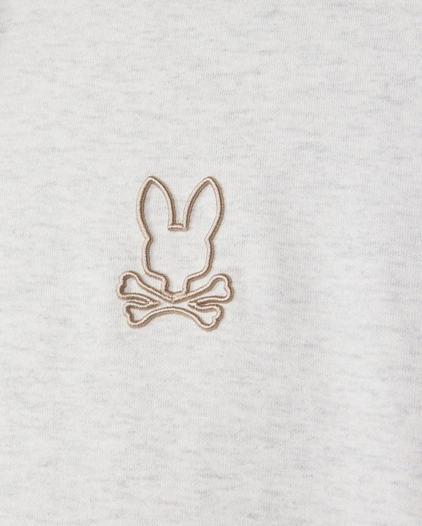 Highlighted in a detailed close-up, the MENS JAMES PREMIUM HOODIE (B6H789D200) from Psycho Bunny features an embroidered bunny design with a rabbit's head outline above two crossed bones. Beige thread contrasts subtly against the gray jersey fabric, infusing stylish warmth into this premium piece.