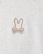 Highlighted in a detailed close-up, the MENS JAMES PREMIUM HOODIE (B6H789D200) from Psycho Bunny features an embroidered bunny design with a rabbit's head outline above two crossed bones. Beige thread contrasts subtly against the gray jersey fabric, infusing stylish warmth into this premium piece.