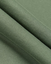 A close-up of the green fabric, resembling the cozy texture of a Psycho Bunny MENS PACIFIC CHENILLE HOODIE (B6H930D200), showcases its smooth feel and fine knitting. The folded fabric highlights its softness and uniform weave, much like luxurious chenille embroidery.