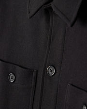 Close-up of the Psycho Bunny MENS BEDFORD SHIRT JACKET - B6J290B200 in black, showcasing two dark buttons and dual chest pockets. The fabric exhibits a textured appearance analogous to work-jacket style, with the men's jacket neatly buttoned.