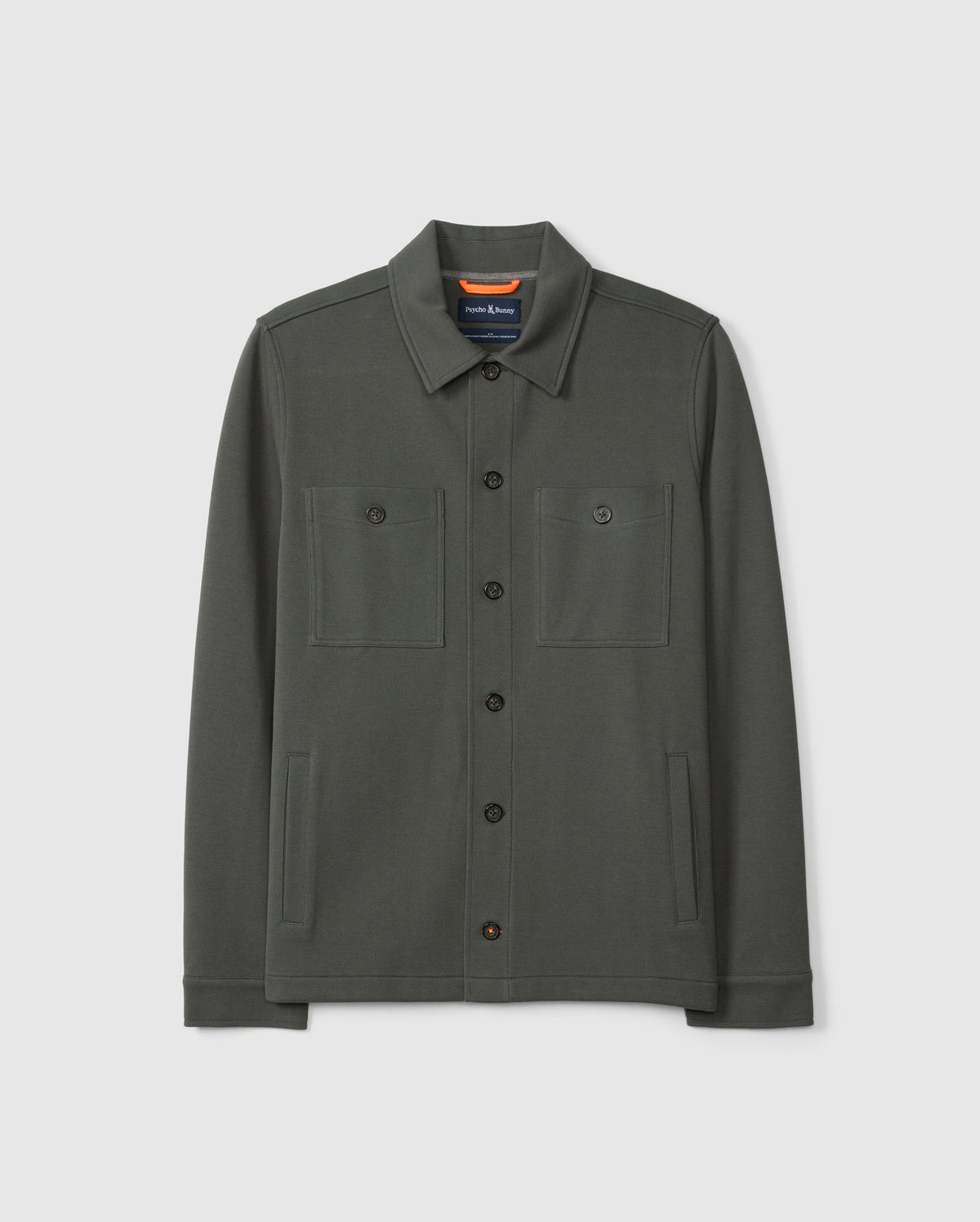 Introducing the MENS BEDFORD SHIRT JACKET - B6J290B200 by Psycho Bunny: a dark green shirt jacket made from a cotton-blend fabric. It includes a collar, two chest pockets, and two side pockets. Its understated design offers a casual and urban look, beautifully showcased against a plain background.