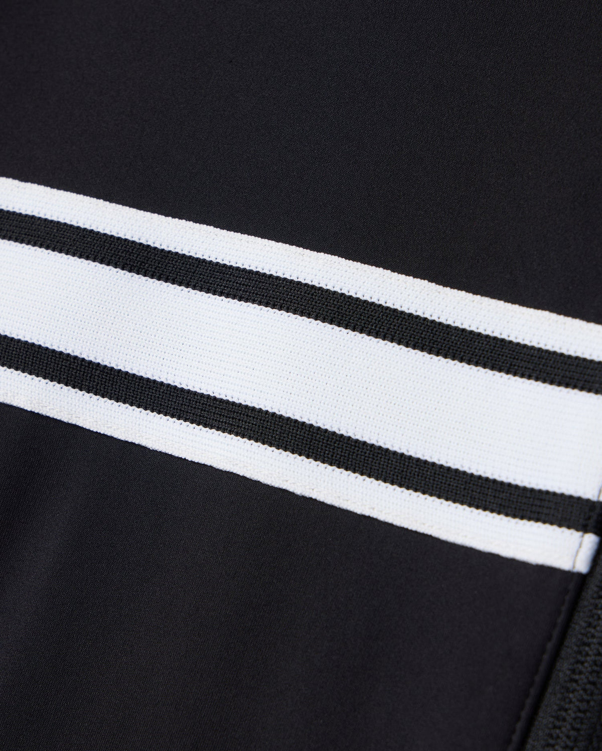 Close-up of the Psycho Bunny MENS TERRELL SPORT ZIP UP JACKET - B6J643C200, featuring a versatile black fabric design with two horizontal white stripes. The smooth and sleek appearance highlights the modal-blend knit texture.