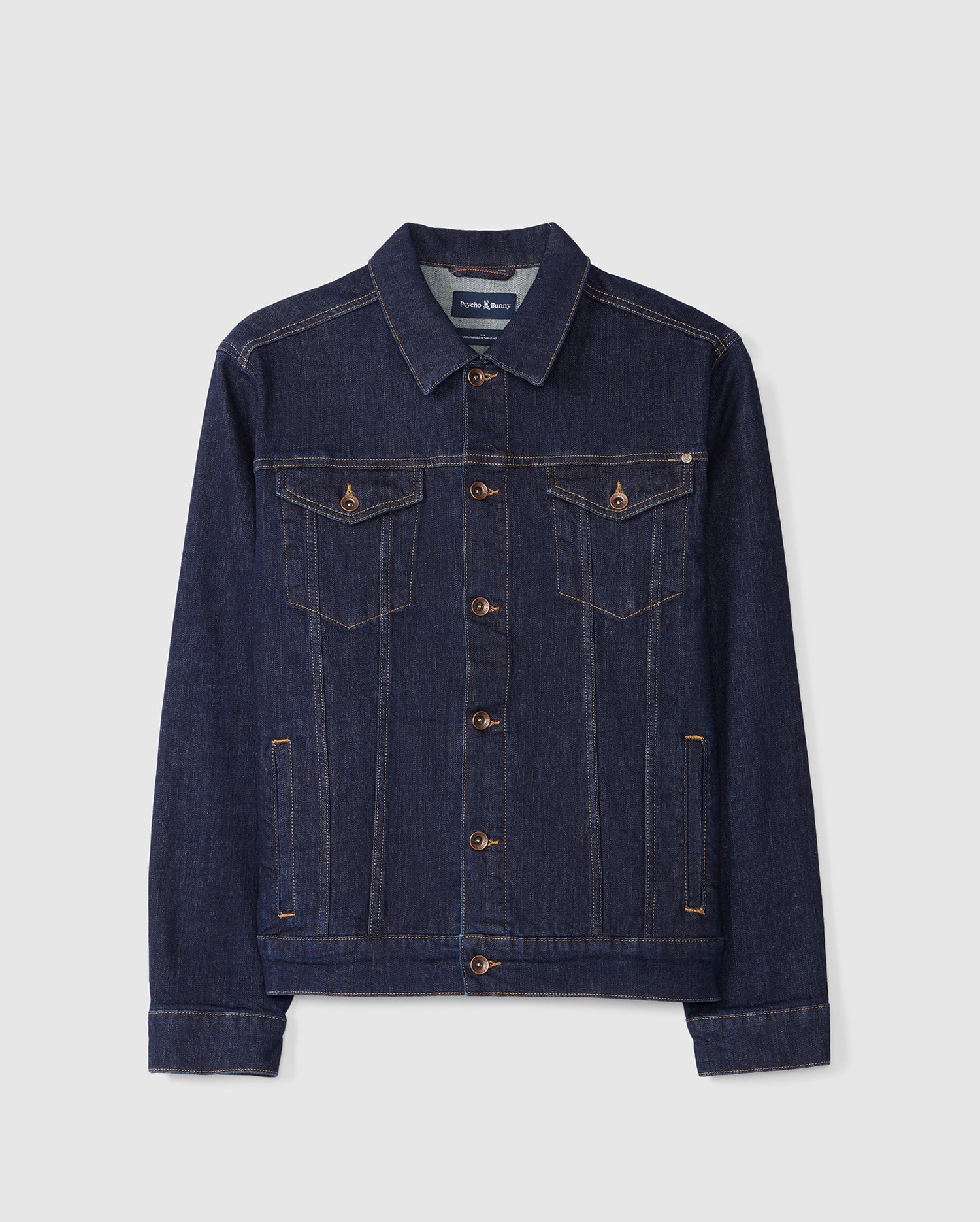 Introducing the Psycho Bunny MENS PATHE DENIM JACKET - B6J741X1CO: This classic men's dark blue denim jacket showcases a pointed collar and button-down design. It features two chest pockets with buttoned flaps, embroidered details, and contrast stitching for an adjustable fit, all presented against a plain white background.