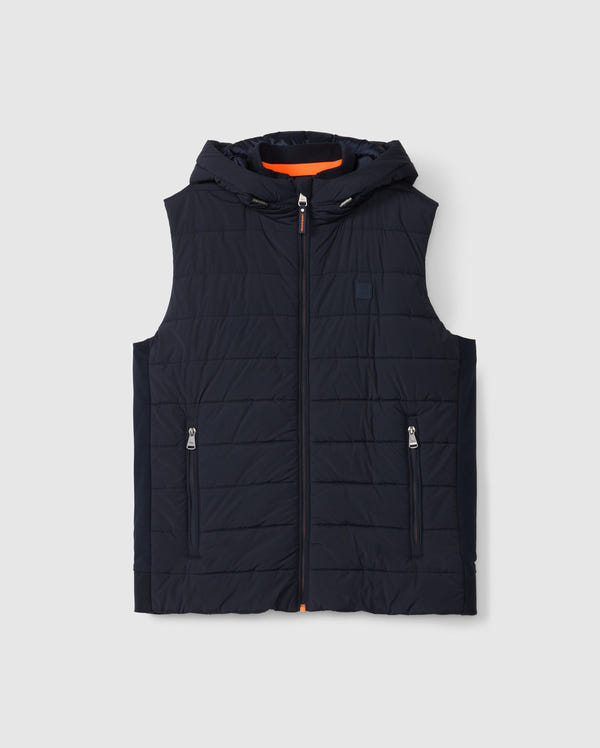 The Psycho Bunny MENS MALCOLM MIXED MEDIA VEST (B6J861D200) is a black quilted vest with a hood, front zipper, and two zippered pockets. Its orange lining adds a stylish contrast against the plain white background.