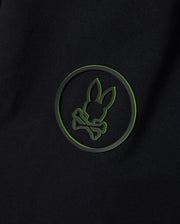 The edgy and modern design of a black background with a green outlined circle featuring a silhouette of bunny ears and crossbones pairs perfectly with the versatile style of the Psycho Bunny MENS MYKEL MIXED MEDIA JACKET - B6J875D200.