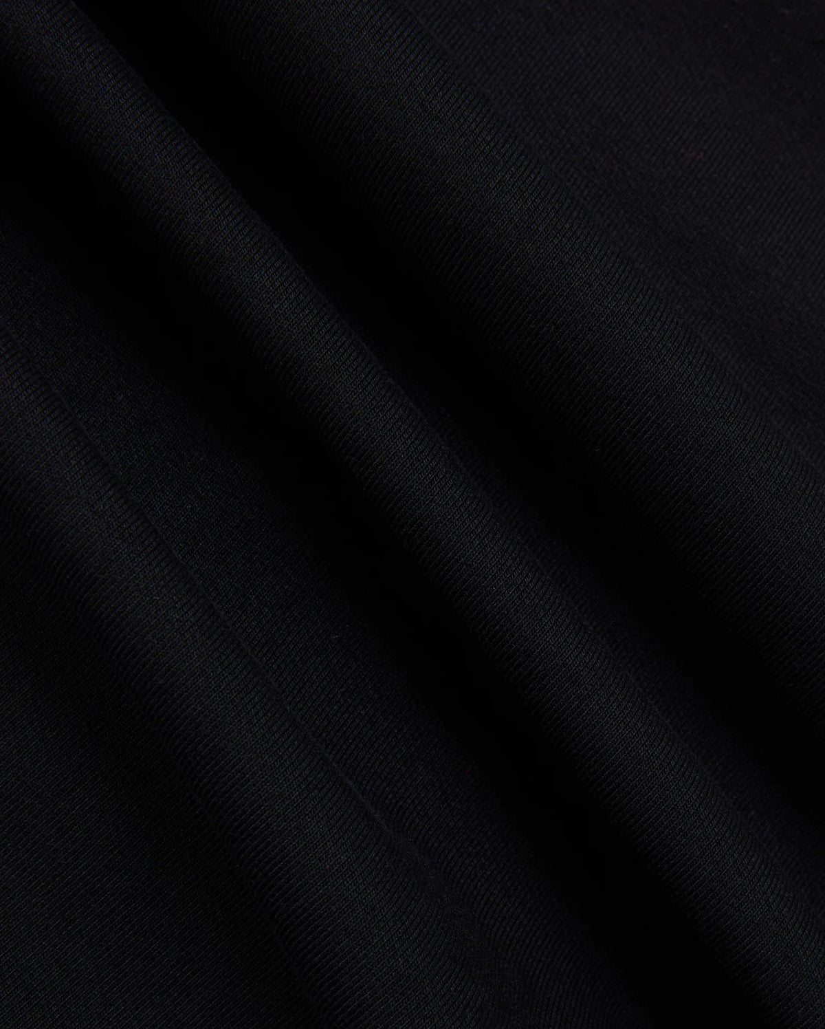 A close-up of the fabric from the Psycho Bunny MENS MYKEL MIXED MEDIA JACKET - B6J875D200 reveals its smooth texture and subtle diagonal lines. The material appears soft with a slight sheen, capturing the way light falls on its surface, highlighting the elegance of this staple men's jacket.