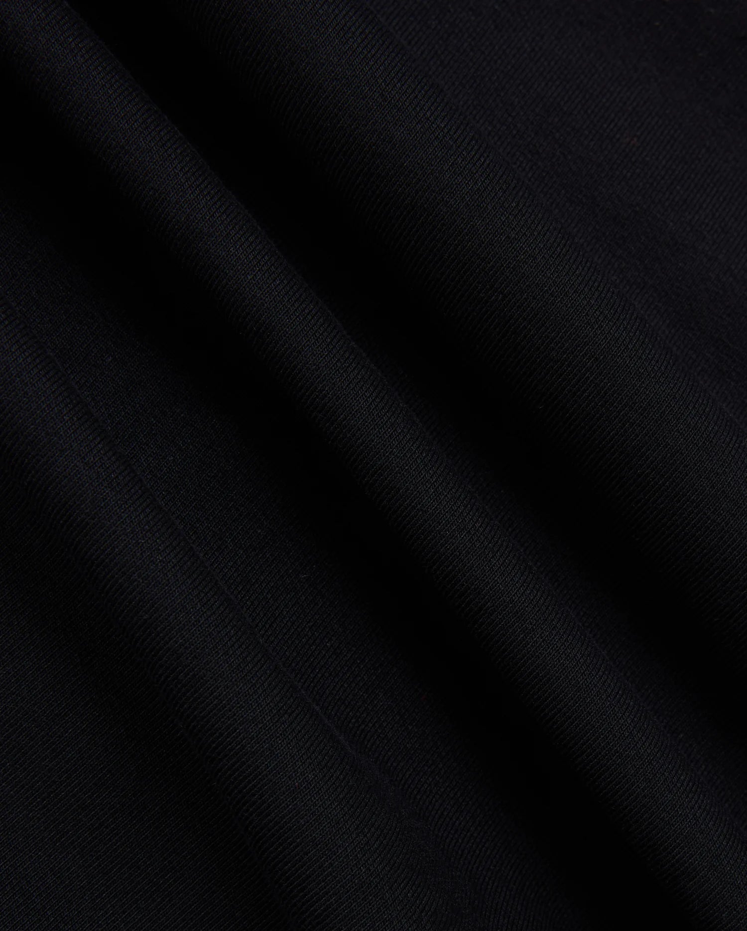 A close-up of the fabric from the Psycho Bunny MENS MYKEL MIXED MEDIA JACKET - B6J875D200 reveals its smooth texture and subtle diagonal lines. The material appears soft with a slight sheen, capturing the way light falls on its surface, highlighting the elegance of this staple men's jacket.