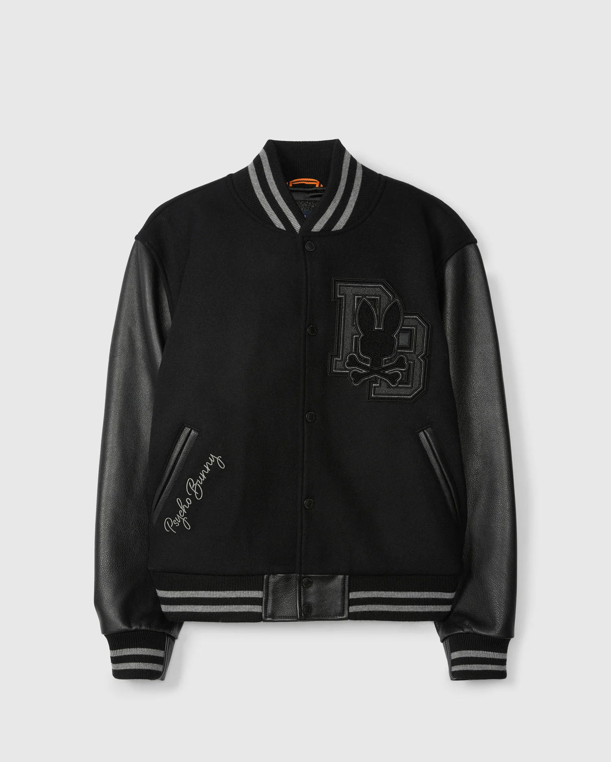 Presenting the Psycho Bunny Men's Brayden Wool Leather Varsity Bomber (B6J876D200): a sleek black jacket featuring eye-catching leather sleeves, striped cuffs, and a striking embroidered patch on the chest with initials and a rabbit silhouette. The phrase "Playboy Bunny" is elegantly stitched near the pocket for added flair.