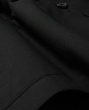 Close-up of the Psycho Bunny MENS HILLCREST PADDED SHACKET - B6J936D200, featuring sleek black fabric with button details. The dense, finely woven material has a smooth, glossy texture and subtle lighting emphasizes its luxurious finish.