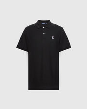 A Psycho Bunny men's black piqué polo shirt featuring a collar with two buttons and a white rabbit emblem with crossed ears and skull on the left chest. The diamond-knit fabric provides classic style, set against a light gray background. Model: MENS CLASSIC PIQUE POLO SHIRT - B6K001ARPC.