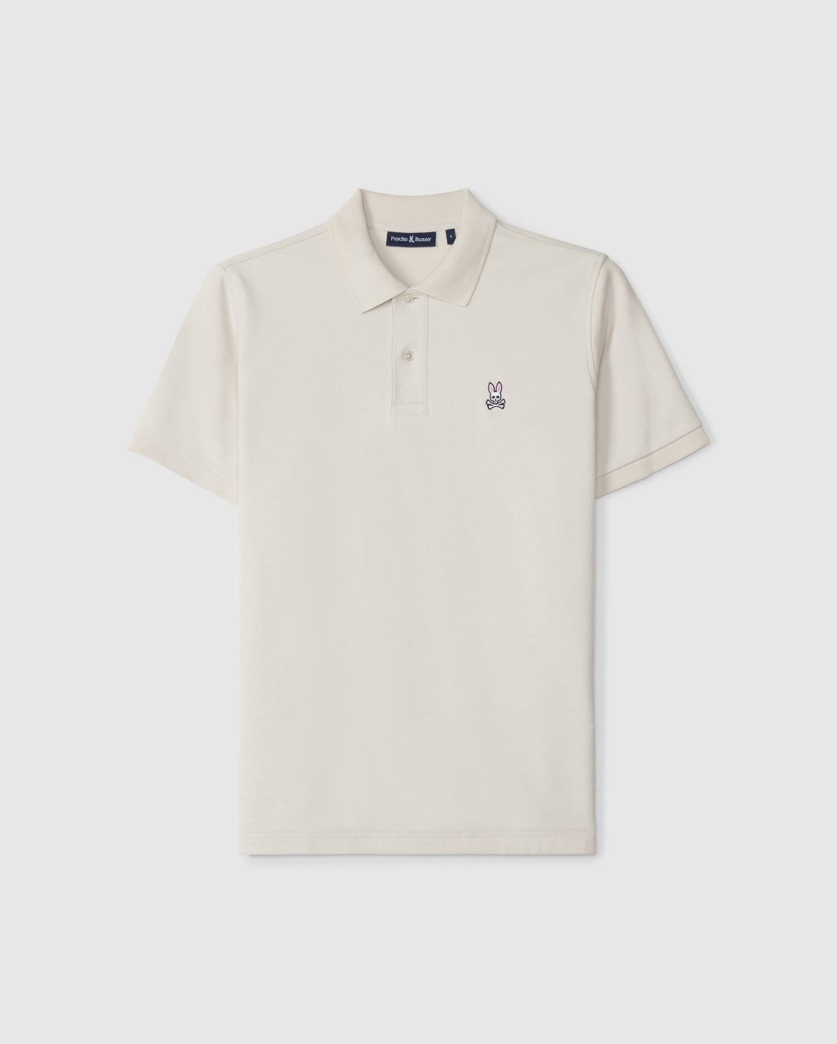 A timeless men's classic pique polo in luxurious Pima cotton, this plain, short-sleeved shirt in off-white features a collar, two buttons, and a small embroidered bunny logo on the left chest. The product is the MENS CLASSIC PIQUE POLO SHIRT - B6K001B200 by Psycho Bunny.