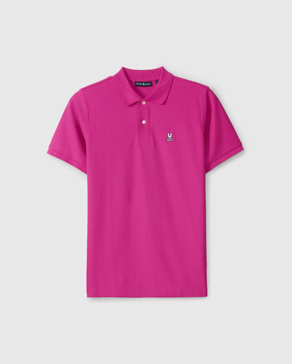 The Men's Classic Pique Polo Shirt (B6K001D200) by Psycho Bunny is a vibrant pink design, expertly crafted in Peru from 100% Pima cotton. It includes a small embroidered bunny skull and crossbones logo on the left chest, featuring a classic collar and a three-button placket. The shirt is set against a simple white background.