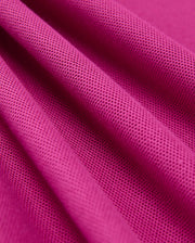 Close-up of a pink textured fabric with small perforations, crafted from 100% Pima cotton. This material, originating from Peru, is elegantly draped to form soft folds and shadows that accentuate the details and pattern of Psycho Bunny's Mens Classic Pique Polo Shirt (B6K001D200).