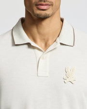 Partially visible is a person in a regular fit MENS ELDORADO PIQUE POLO by Psycho Bunny. Made from luxurious Peruvian Pima cotton, it features a collar and the iconic bunny above crossed bones patch, emphasizing its timeless appeal.