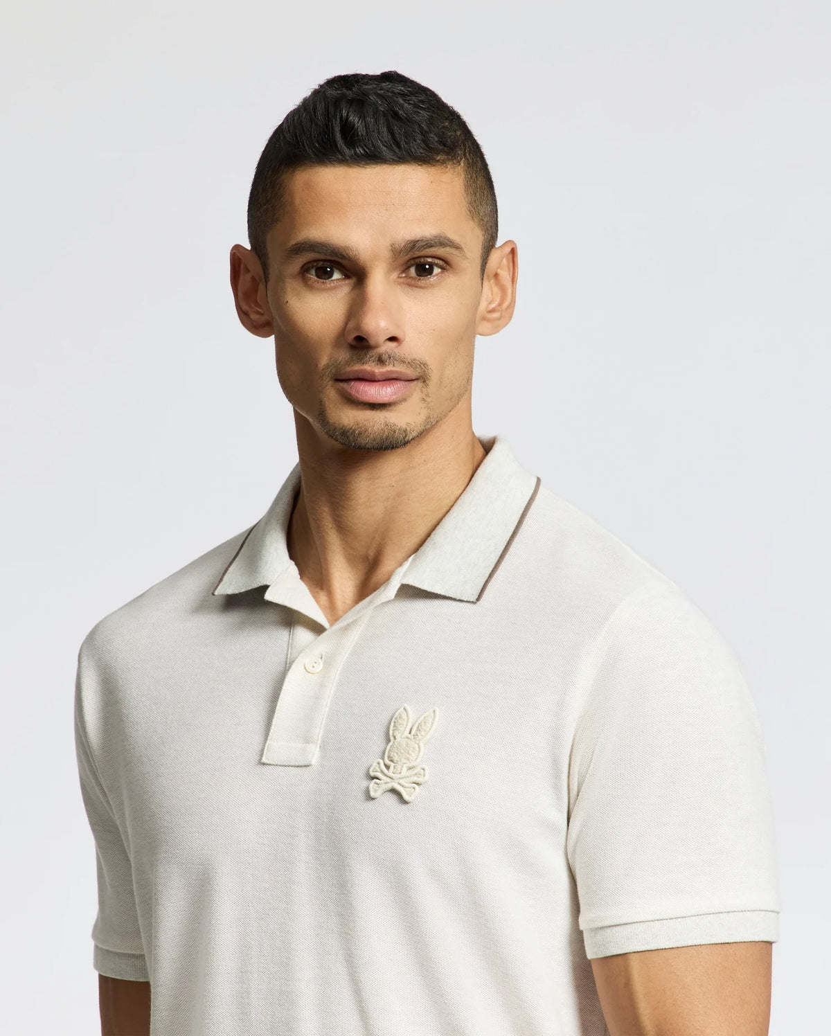 A man with short hair wears a Psycho Bunny MENS ELDORADO PIQUE POLO - B6K105E200, crafted from soft Peruvian Pima cotton, featuring an embroidered rabbit logo, against a plain background.