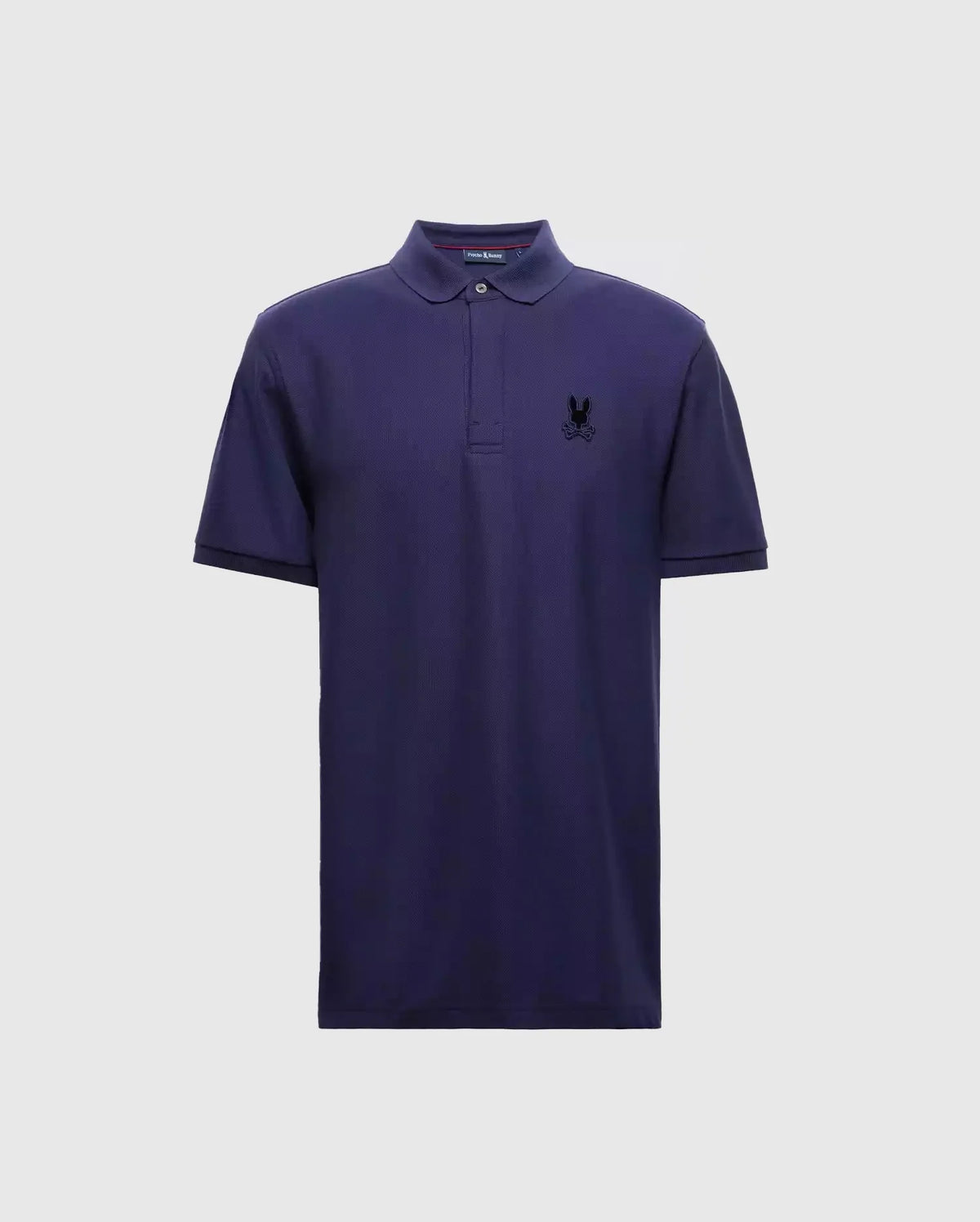 The Psycho Bunny MENS BRANSON PIQUE POLO - B6K108E200 is a premium quality navy blue polo for men, complete with short sleeves and a collar. It boasts a small black insignia on the left chest, providing an elegant contrast to the light gray background.
