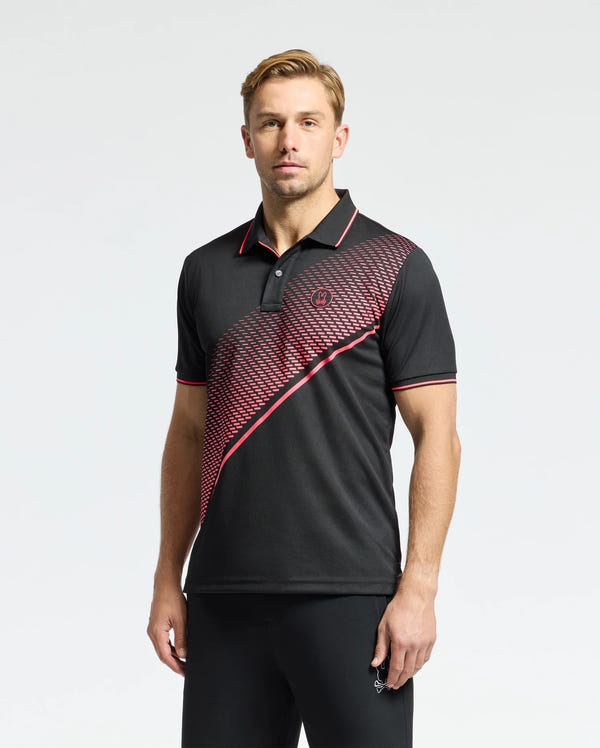 A man with short light brown hair poses against a plain background, wearing the Psycho Bunny MENS MACK SPORT PIQUE POLO (B6K321E200), a black shirt with red accents and a diagonal red patterned stripe. Crafted for comfort with Peruvian skill, it features moisture-wicking technology.