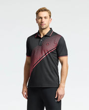 A man with short light brown hair poses against a plain background, wearing the Psycho Bunny MENS MACK SPORT PIQUE POLO (B6K321E200), a black shirt with red accents and a diagonal red patterned stripe. Crafted for comfort with Peruvian skill, it features moisture-wicking technology.