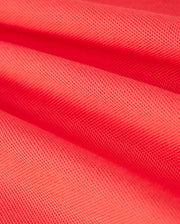 Close-up of vibrant red fabric from the MENS GRANBURY PIQUE POLO - B6K400C200 by Psycho Bunny. The image highlights the intricate pattern and structure, showcasing its rich color and detailed stitching. The Pima cotton fabric appears soft and flexible, folded into gentle waves like a well-crafted polo shirt.