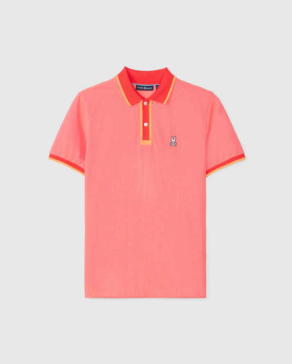The Psycho Bunny MENS WOODWAY OXFORD POLO - B6K405C200 is a brightly colored short-sleeve polo shirt in coral pink with red and yellow trim on the collar and sleeves. Made from a soft Pima cotton-blend, it features a classic two-button placket and a small embroidered bunny logo on the left chest.