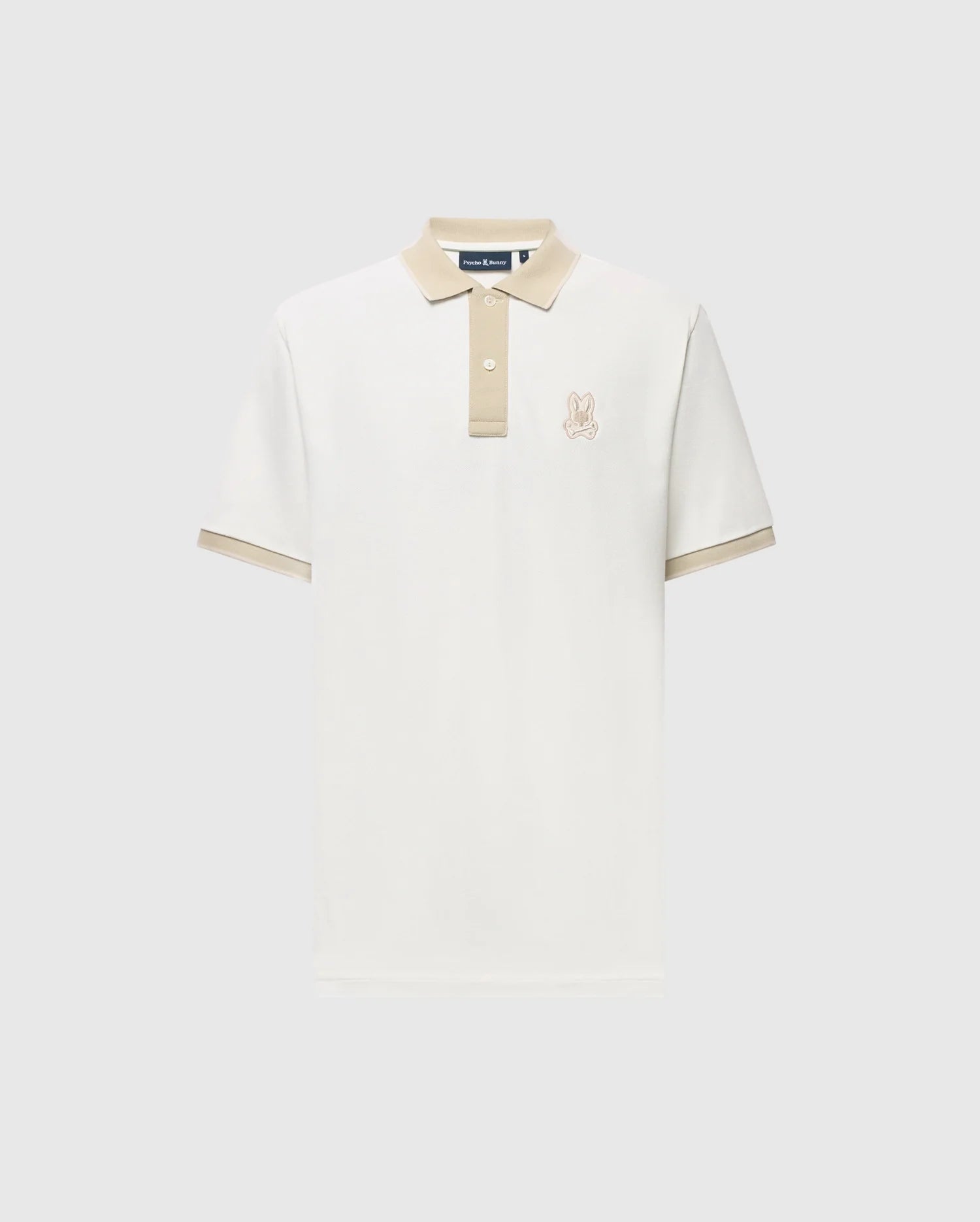 Introducing the Psycho Bunny Men's New Castle Pique Polo (B6K487F200): a white, 100% Pima Cotton shirt with a beige collar and sleeve trim, featuring an embroidered bunny logo on the left chest and buttons on a light gray background.