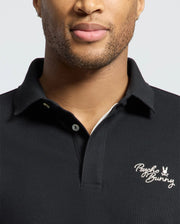 Wearing the MENS DESERT PIQUE POLO by Psycho Bunny, a person exudes timeless style with its embroidered logo on the chest, made from luxurious Pima cotton.