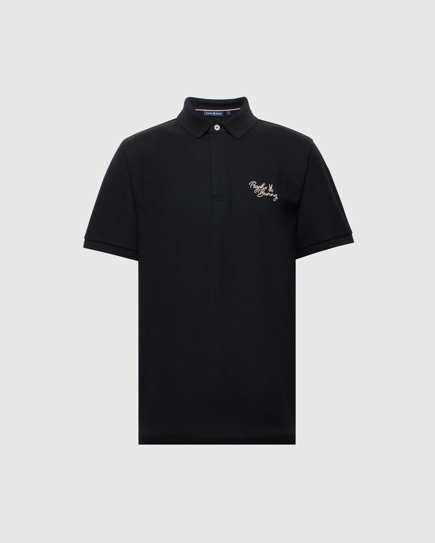 The Psycho Bunny MENS DESERT PIQUE POLO - B6K506F200 in black features a classic collar, two-button neckline, and white embroidered text on the left chest. Made from premium Pima cotton, it offers comfort and timeless style against a light gray backdrop.