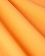 Close-up image of folded orange fabric with a fine, textured surface. The Pima cotton material is arranged in soft, diagonal folds, showcasing its smooth, vibrant appearance. Ideal for crafting a Psycho Bunny MENS BELTON PIQUE POLO - B6K575C200 with an embroidered Bunny logo.