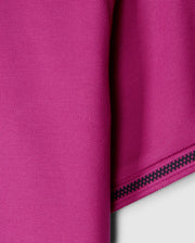 Close-up of the pink Pima cotton fabric from the Psycho Bunny MENS RIVIERA PIQUE POLO SHIRT - B6K640C200, showcasing a textured pattern with a folded edge on the right. A decorative black zigzag stitch enhances the edge, contrasting beautifully with the vibrant material, reminiscent of luxurious Riviera polo craftsmanship.