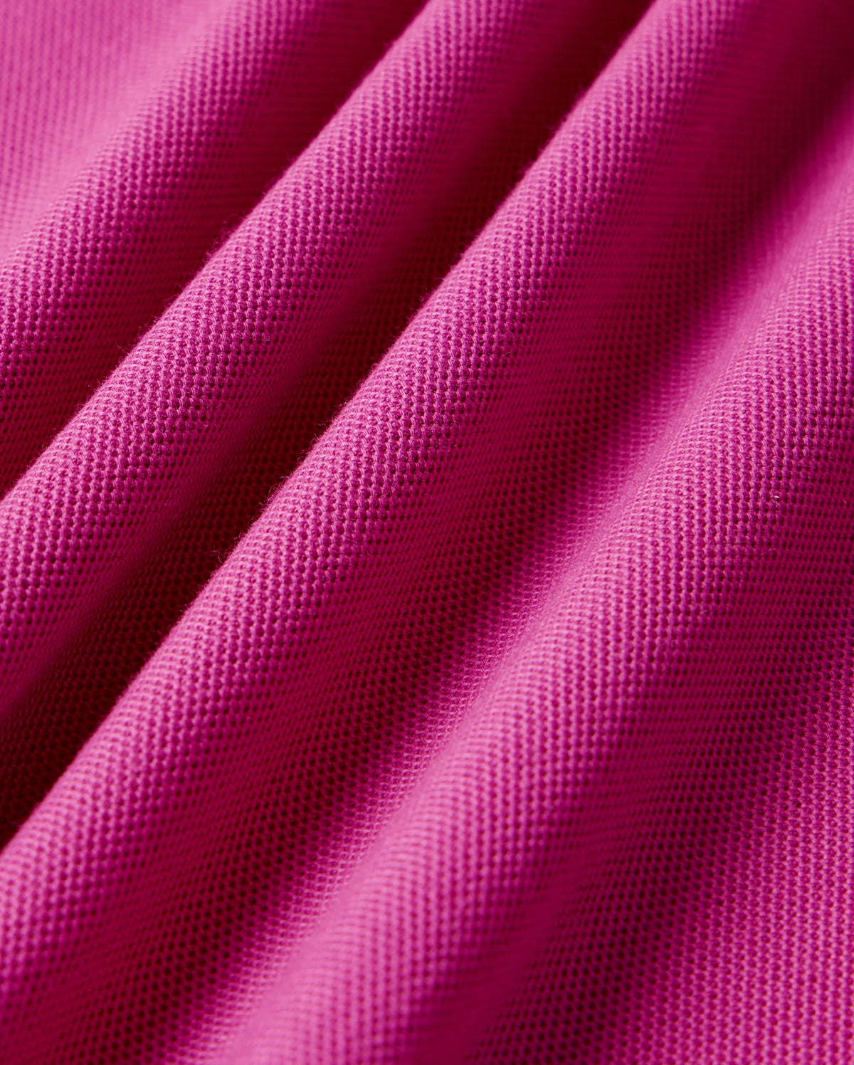 A close-up of the Psycho Bunny MENS RIVIERA PIQUE POLO SHIRT - B6K640C200 in pink showcases the textured Pima cotton fabric with diagonal lines, offering a soft touch and subtle raised patterns that enhance depth and dimension.