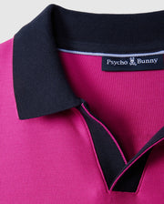 Close-up of a magenta collared Psycho Bunny MENS RICHARDS JOHNNY COLLAR PIQUE POLO SHIRT - B6K641C200 with black trim around the collar. Made from breathable Pima cotton, the inside label reads "Psycho Bunny" with a small bunny logo above the text. The solid pattern stands out against the plain light gray background.