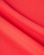 Close-up of vibrant red fabric with a subtle grid-like texture, folded in soft waves. The material appears smooth and slightly shiny, resembling diamond-knit Pima cotton, suitable for the MENS KAYDEN PIQUE POLO - B6K675C200 by Psycho Bunny.