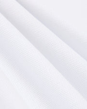 Close-up of a white, textured MENS KINGSTON PIQUE POLO SHIRT - B6K764D200 by Psycho Bunny, made from soft Pima cotton with a subtle waffle pattern. The fabric is shown in folds, highlighting its texture and softness. The image captures the intricacies of the material, emphasizing the small, raised squares that create the waffle effect.