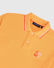 An orange men's Winton polo shirt made from Peruvian Pima cotton, featuring white and orange stripes on the collar. It has a white embroidered bunny logo on the left chest and a "Psycho Bunny" label inside. The shirt is laid flat against a white background, showcasing its premium diamond-knit piqué fabric. This product is the MENS WINTON PIQUE POLO SHIRT - B6K841A2PC by Psycho Bunny.
