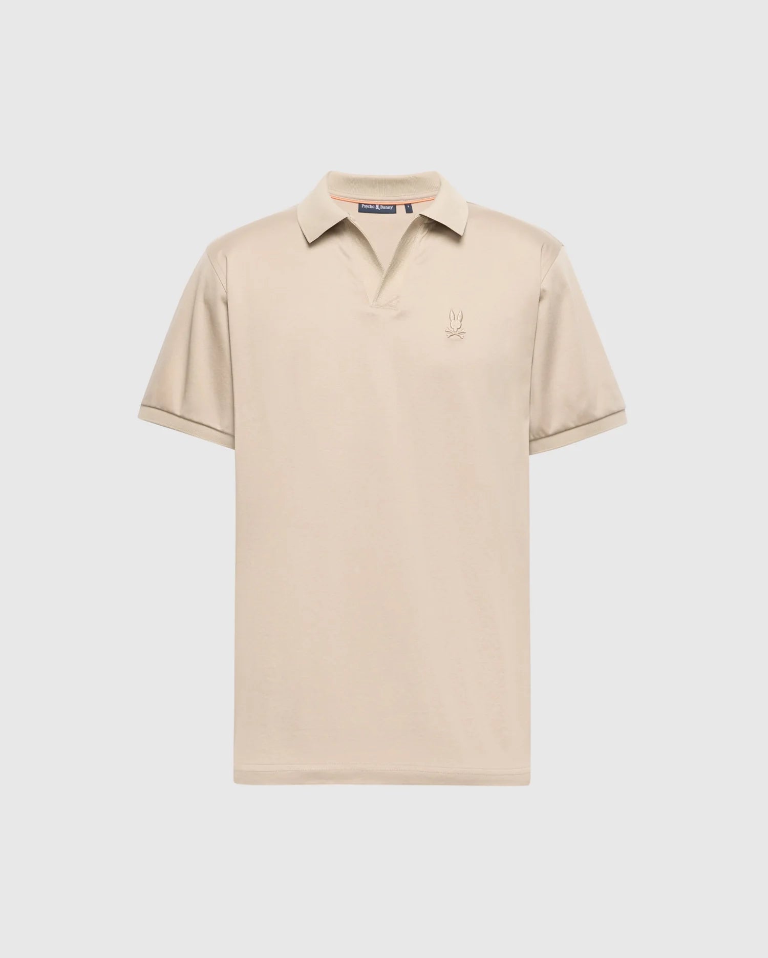 The Psycho Bunny MENS BROADWAY PIMA INTERLOCK JOHNNY COLLAR POLO - B6K891D200 is a beige polo shirt made from soft pima cotton. It features short sleeves, a collar, and a small logo on the chest, showcased against a plain white background.