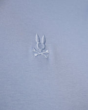 The MENS BROADWAY MERCERIZED PIMA POLO SHIRT by Psycho Bunny showcases a close-up of durable gray luster fabric with an embroidered design featuring a bunny head above two crossed bones.