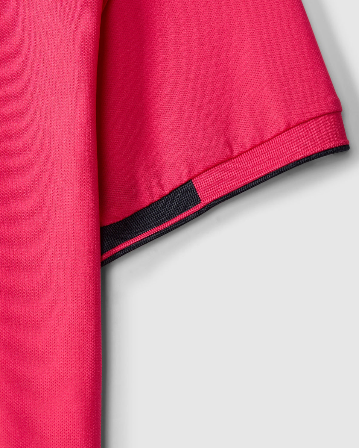 The Psycho Bunny MENS BELLEVUE SPORT POLO SHIRT - B6K905D200 is featured in a close-up shot against a gray background, illustrating its pink short sleeves accented with black trim. This men's athletic knit polo is made from textured fabric that highlights the weave of the material, offering both style and versatility for various activities.