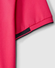 The Psycho Bunny MENS BELLEVUE SPORT POLO SHIRT - B6K905D200 is featured in a close-up shot against a gray background, illustrating its pink short sleeves accented with black trim. This men's athletic knit polo is made from textured fabric that highlights the weave of the material, offering both style and versatility for various activities.