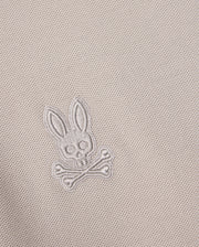 Close-up of the Pima cotton fabric on the Psycho Bunny MENS MALTON PIQUE POLO SHIRT - B6K950D200, showcasing an embroidered design featuring a skull with bunny ears above two crossed bones. The embroidery blends seamlessly into the diamond pique pattern, creating a subtle yet distinctive Psycho Bunny signature.