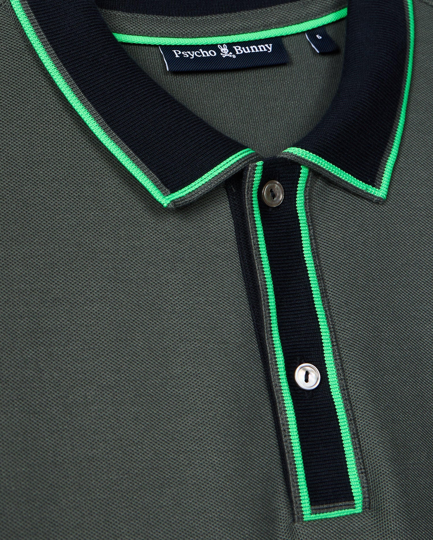 Close-up of the stylish Men's Kent Pique Polo Shirt in dark green, featuring a black collar and neon green trim. This Psycho Bunny shirt showcases a two-button placket and a small tag near the collar with the brand name.