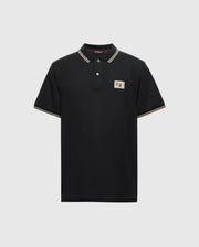 A Psycho Bunny Men's Monroe Pique Polo (B6K964D200) in black Pima cotton, designed with white and gold trim on the collar and sleeves. It includes a small beige patch with an emblem on the left chest and is complemented by three Mother-of-Pearl buttons along the placket, all set against a plain white background.