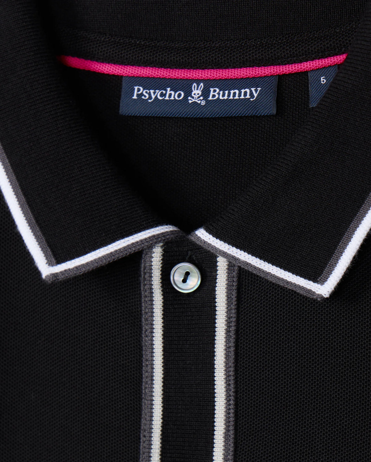 Close-up of the Psycho Bunny MENS KENT LONG SLEEVE PIQUE POLO (B6M935D200) in black, crafted from soft Pima cotton. The shirt features a buttoned front, with white and light grey trim along the collar and placket, adding a subtle rugby style flair.