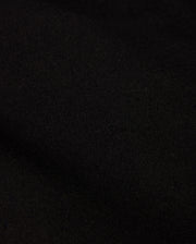 A close-up of the dark, textured fabric from the MENS STAFFORD WOOL BLEND COAT - B6N551D200 by Psycho Bunny reveals a soft, matte finish. The dense, finely woven material displays subtle shading variations due to lighting.
