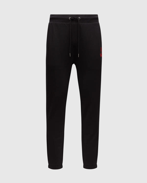 The Psycho Bunny MENS PIERCE ESSENTIAL FRENCH TERRY SWEATPANT - B6P136E200 are black sweatpants featuring a drawstring waistband and tapered legs. A small red embroidered logo is positioned on the left upper thigh, providing both style and comfort. Set against a plain white background, these joggers are an essential addition to any men's lounge collection.