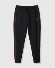 The MENS TRAVIS TRACK PANT - B6P143D200 by Psycho Bunny are black jogger pants with red stitching detail along the outer seams. Crafted from a high-quality cotton-blend, they include drawstrings at the waistband and ribbed cuffs for added comfort. A small red Psycho Bunny logo is embroidered on the upper left side near the pocket, against a plain white background.