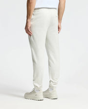 A person is shown from the back, wearing Psycho Bunny's light gray Men's Eldorado Brush Back Jogger (B6P285E200) with matching sneakers against a plain background, highlighting the casually styled lower half made of brushback cotton fabric.