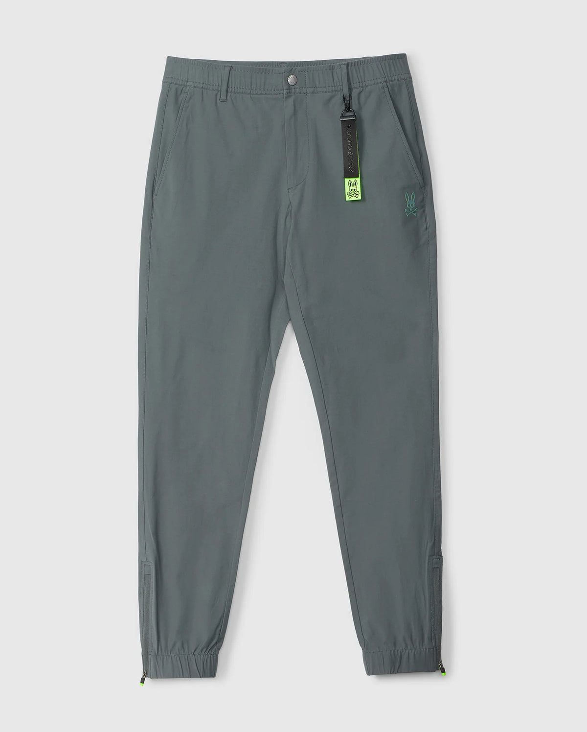 Gray jogger pants with elastic cuffs, an elasticized waistband, and a small Psycho Bunny logo on the left thigh. A neon green Psycho Bunny tag is attached to the waistband. The background is plain white.